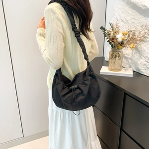 Fashionable black nylon drawstring tote bag with pleated shoulder straps worn by model