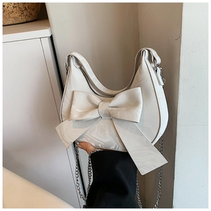 Detail view of cream handbag featuring marble texture and a large decorative bow