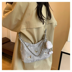 Detail of silver pleated shoulder bag featuring gold butterflies and a plush charm