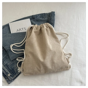 Detail view of beige corduroy drawstring backpack with soft texture and white cotton ropes