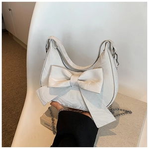 Detail of white half-moon underarm bag with large bow and marble textured finish
