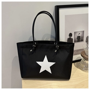 Detail of black tote bag featuring a white star print and stylish drawstring accents