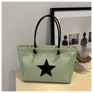 Detail view of a light green tote bag featuring a black star print and metal eyelets