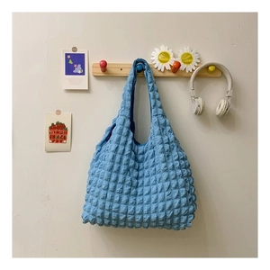 Detail of the sky blue popcorn texture fabric on this spacious tote bag hanging on a hook