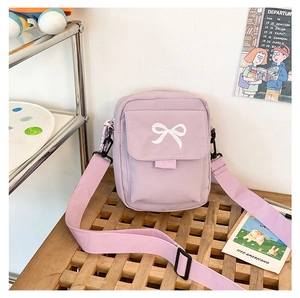 Close-up of lilac canvas crossbody bag featuring cute white bow embroidery and front pocket