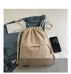 Detail of beige corduroy drawstring backpack with thick cotton ropes and woven label
