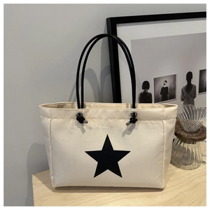 Minimalist beige tote bag featuring a bold black star print and slim shoulder straps
