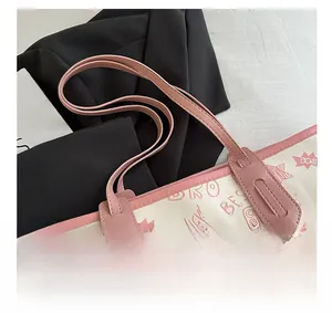 Detail of canvas tote bag showing pink leather handles and playful graffiti print