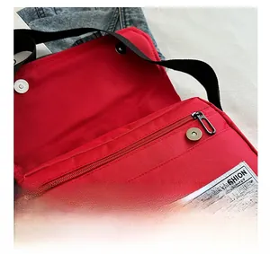 Detail of red oxford crossbody bag showing double magnetic buckles and front zipper pocket