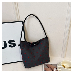 Close-up of dark grey canvas bucket bag with red polka dots and shoulder strap detail