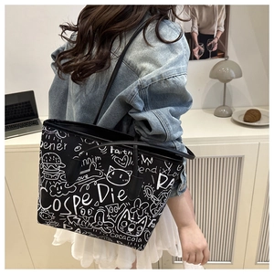 Detail of high-capacity graffiti tote bag with white street art patterns on black canvas