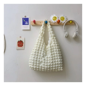 Detail of creamy white bubble textured tote bag hanging with stylish lifestyle accessories