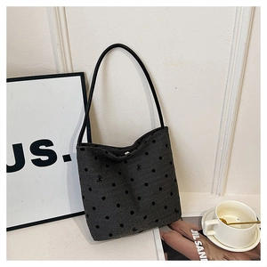 Detailed view of gray polka dot tote bag with bow embroidery in a minimalist setting