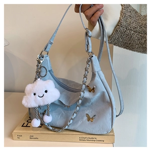Detail of light blue pleated tote bag with metal butterfly and smiley cloud charm