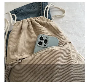 Detailed view of corduroy drawstring backpack front pocket with mobile phone storage