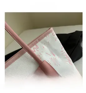 Close-up of the pink leather handles and graffiti print on the white canvas tote bag