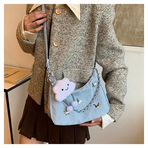 Detail of light blue crescent shoulder bag with silver butterfly charms and plush pendant