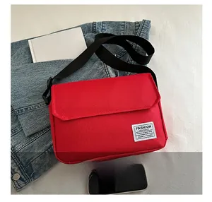 Detail of red oxford canvas messenger bag showing white label and black nylon strap