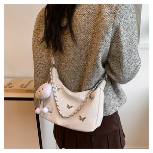 Detail of white half-moon shoulder bag with silver butterfly charms and metal chain