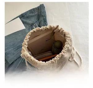 Detail view of corduroy bucket bag interior filled with books, wallet, and umbrella