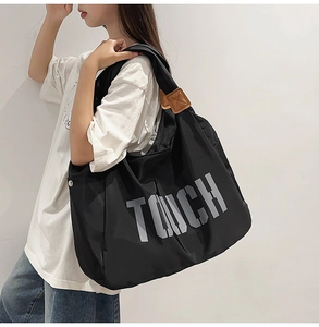 Dettaglio della borsa tote in nylon nero con stampa TOUCH grigia e finiture in pelle