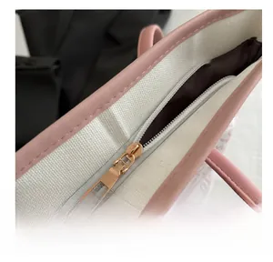 Macro shot of smooth golden metal zipper and pink leather edge on a canvas tote bag