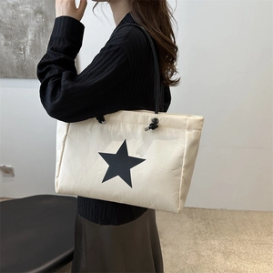Minimalist beige tote bag with black star print and long shoulder straps for casual use