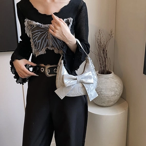 Silver crescent bow handbag with marble texture held by model in stylish outfit