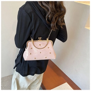 Model wearing a pink kiss-lock bag with heart rivets and a gold metal chain strap