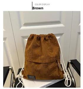 Close-up of brown corduroy drawstring backpack featuring a black Fashion logo patch