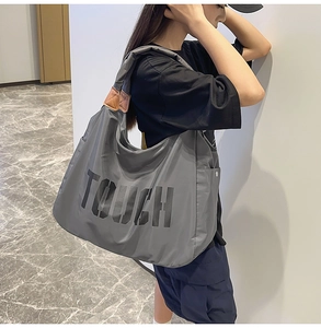 Dettaglio borsa tote in nylon grigio con accenti in pelle marrone e stampa TOUCH