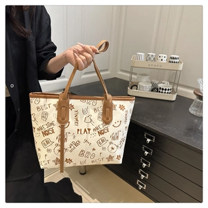 Detail of canvas tote bag featuring brown leather trim and cute cartoon graffiti prints