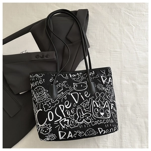 Detail of black tote bag with white street graffiti featuring cats, burgers, and letters