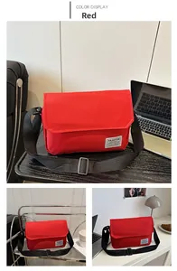 Close-up of red Oxford fabric messenger bag featuring a white Fashion Instinct label