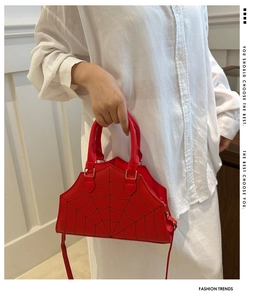 Close-up of red spider web embroidered handbag featuring matte leather and handles
