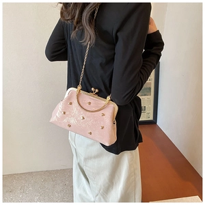 Detailed back view of model carrying pink glitter leather handbag with heart-shaped metal studs