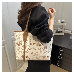 Detailed side view of large canvas tote bag with brown leather straps and graffiti prints