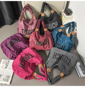 Varie borse tote in nylon colorate con scritta TOUCH esposte con accessori lifestyle