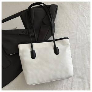 Detail of minimalist contrast canvas tote bag with black straps on a textured fabric background