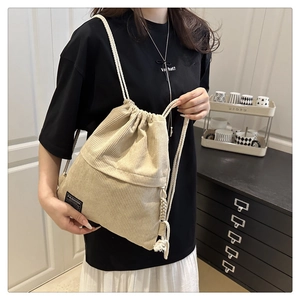 Detail of drawstring corduroy backpack in beige featuring a fashion woven label