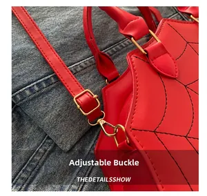Detail of red crossbody bag showing adjustable shoulder strap with gold metal buckle