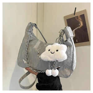 Detail view of silver crescent bag with textured metallic finish and chain decoration