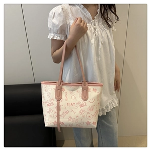 Detail showing colorful tote bag with playful graffiti prints and pink leather handles