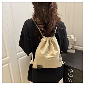 Detailed texture of beige corduroy drawstring backpack with front pocket and fashion label