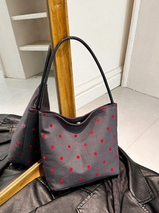 Deep grey polka dot bucket bag with red patterns and slim black leather handles