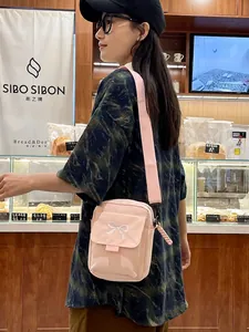 Pink canvas crossbody bag with white bow embroidery and adjustable strap for women