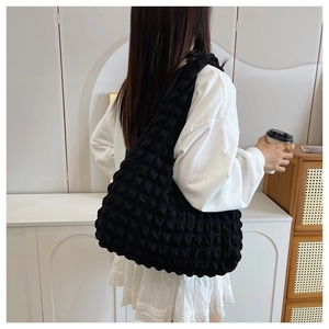 Close-up of a black pleated bubble shoulder bag showing textured fabric and large capacity