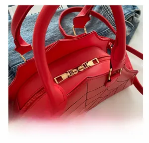 Close-up of dual metal zippers and spider web texture on a red faux leather handbag