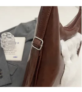 Détail d'une boucle en métal argenté sur cuir marron avec textures en fausse fourrure