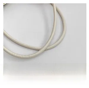 Gros plan sur la bandoulière en cuir blanc crème avec coutures détaillées du sac fourre-tout